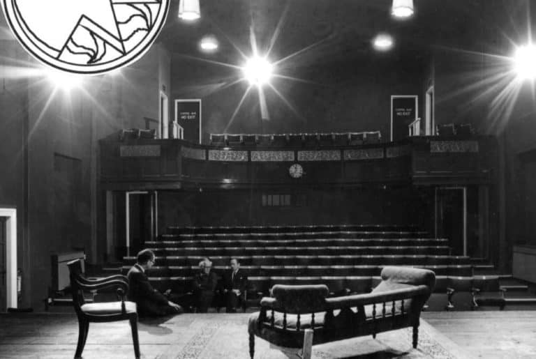 black and white photo of stage and seats and bright stage light